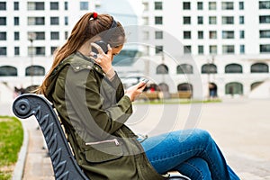 Portrait of young teenager brunette girl with long hair. young woman listening to music using mobile phone sitting on bench
