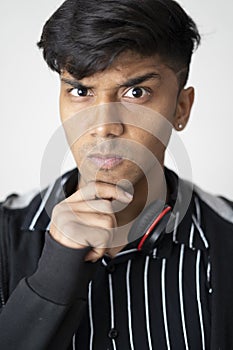 Portrait of young teenager resting chin on fist, clean shave and wearing black jacket against white background