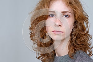 Portrait of young tender redhead teenage girl with healthy freckled skin wearing official dress looking at camera
