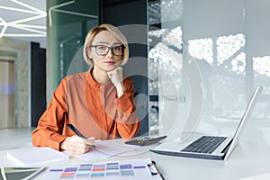 Portrait of young thinking business woman, blonde at workplace inside office concentrating and looking seriously at