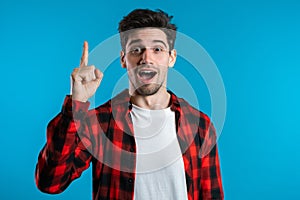 Portrait of young thinking man in red having idea moment pointing finger up