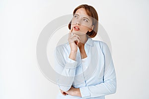 Portrait of young thoughtful woman looking aside at logo, thinking and making choice, pondering decision, standing in