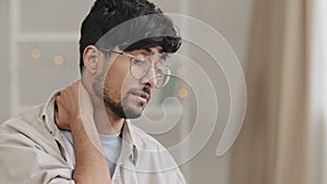 Portrait young tired arabian Indian student business man bearded guy with glasses sitting at home in office on couch