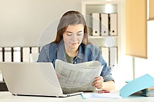 Young trainee reading a newspaper at office photo