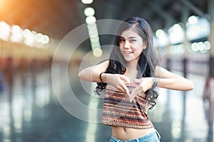 Portrait of young traveler woman waiting for train and posting heart symbol with her hands