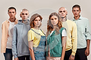 Portrait of young twin brothers and sisters looking at camera, posing together, standing isolated over light background