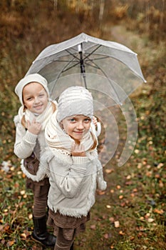 Portrait of young twin girls with an umbrella in the park