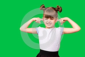 Portrait of young unhappy, stressed little girl covering her ears with fingers calling to stop noise isolated on green