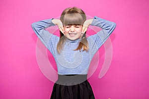 Portrait of young unhappy, stressed little girl covering her ears with hands calling to stop noise isolated on pink