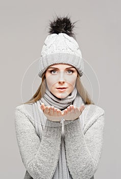 Portrait of a young and beautiful woman in a winter hat over grey background.