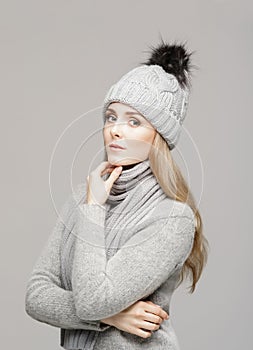 Portrait of a young and beautiful woman in a winter hat over grey background.