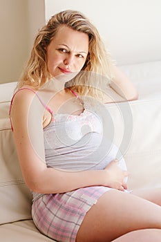 Portrait of young white Caucasian blonde pregnant woman with long hair wearing tshirt and shorts relaxing at home