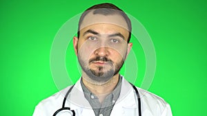 Portrait of young white doctor who looking at camera on green screen background
