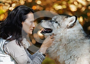 Portrait of a young white woman with an Alaskan Malamute dog in the forest