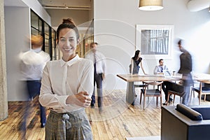 Portrait of young white woman in a busy modern workplace photo