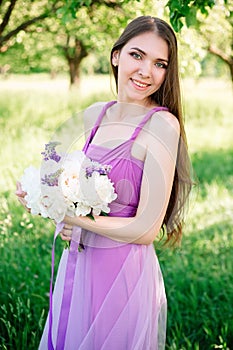 Portrait of a young woman 20s 30s in a light purple dress with a bouquet of peonies in her hands. Graduation, bridesmaid