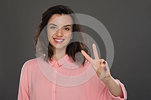 Portrait of a young woman of 30-35 years of model appearance, showing her 2 fingers on her hand.