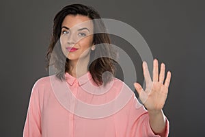 Portrait of a young woman of 30-35 years of model appearance, showing her fingers on her hand.