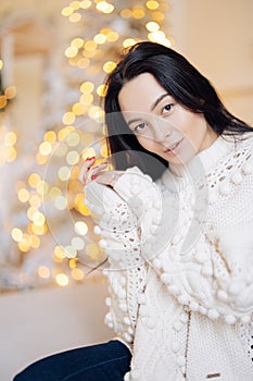 Portrait of young woman against background of Christmas glowing garlands