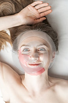 Portrait of young woman with alginic mask on the face in beauty salon. Cosmetic procedure to make skin younger and fresher