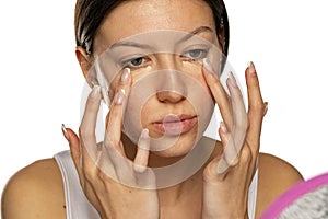 Portrait of young woman applying concealer under her eyes