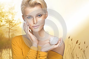 Portrait of young woman applying moisturizer cream