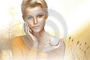 Portrait of young woman applying moisturizer cream