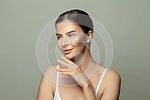 Portrait of young woman applying moisturizer cream on her pretty face. Spa, beauty and skin care concept