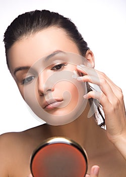 Portrait of young woman applying moisturizer cream on her pretty face - white background. fashion and beauty