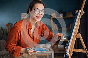 Portrait of young woman artist painting at home creative painting