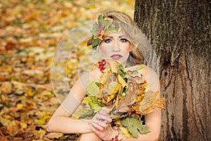 Portrait of young woman. Autumn, dress with leafs. Park