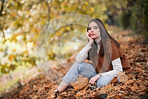 Portrait of young woman with autumn leafs. Romantic girl dream, hold fall maple leaves. Autumnal season.