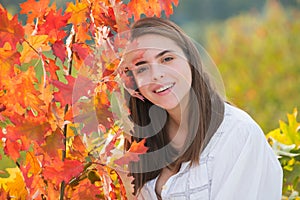 Portrait of young woman with autumn leafs. Romantic girl dream, hold fall maple leaves. Autumnal season.