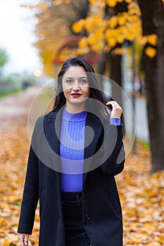 Portrait of a young woman in autumn. She looks to the camera
