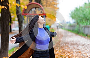 Portrait of a young woman in autumn. She turns with open arms