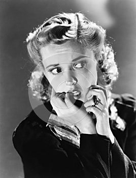 Portrait of a young woman biting her nail and looking frightened photo