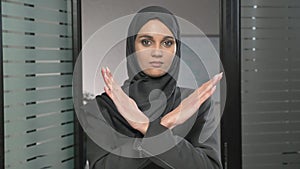 Portrait of Young woman in black hijab showing stop sign, Dislike, Rejecting Gesture, Disagree Sign, Crossing hands 60