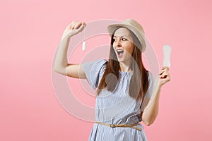 Portrait of young woman in blue dress holding sanitary napkin, tampon for variant safety menstruation days isolated on