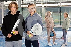 Portrait of a young woman with a boy-athlete standing with padel rackets and balls