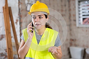 Portrait of young woman builder having telephone conversation