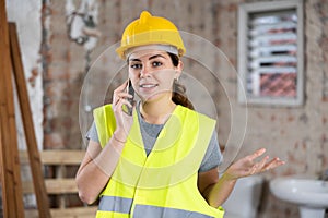 Portrait of young woman builder having telephone conversation