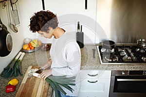 Young woman chopping vegetables in kitchen