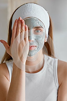 Portrait of young woman with clay facial cosmetology mask