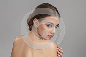 Portrait of a young woman with clean skin. On a gray background