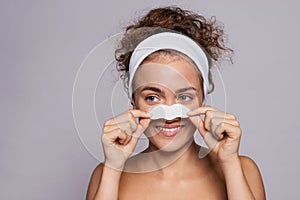 Portrait of a young woman cleaning face in a studio, beauty and skin care.