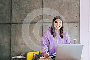 Portrait of young woman college student studying with laptop, distantly preparing for test exam, writing essay doing homework at photo