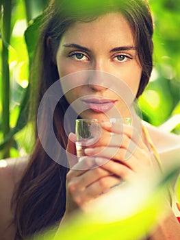 Portrait of young woman in corn field with drinking glass