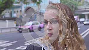 Portrait young woman with curly red hair on city traffic background. Face beautiful woman standing on background moving