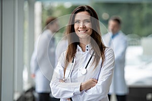 Portrait of young woman doctor with white coat standing in hospital.