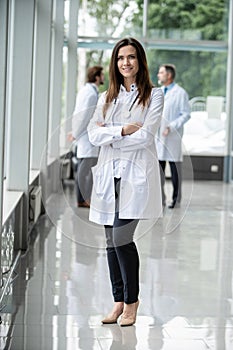 Portrait of young woman doctor with white coat standing in hospital.